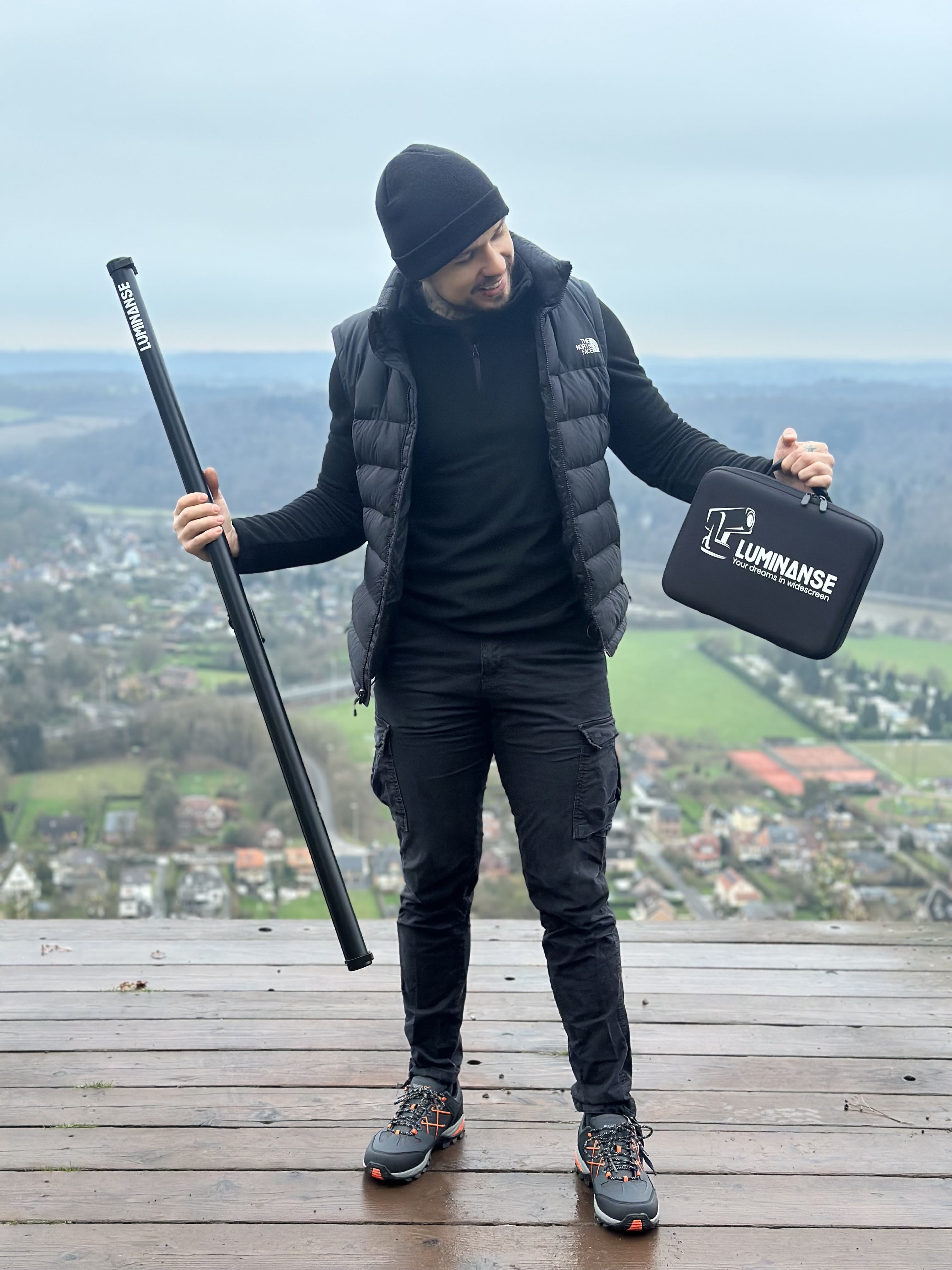 Photo propriétaire site tenant toile de projection et housse de transport sur montagne